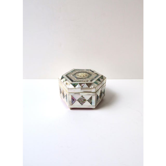 A beautifully crafted hexagonal jewelry box inlaid with luminous mother‑of‑pearl and abalone seashell, executed in the...