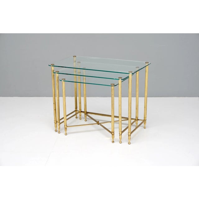 Nest of three glass topped brass coffee tables. Circa 1950