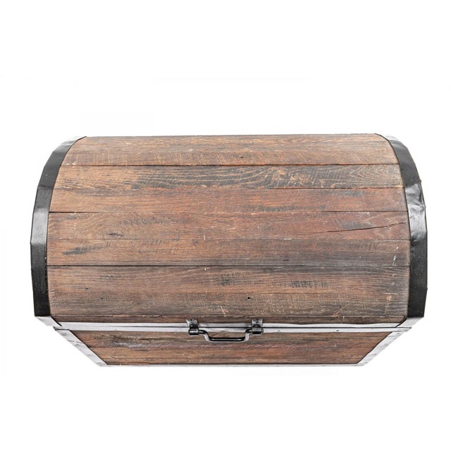 Sturdy and heavy-duty camelback trunk featuring rustic ashen gray toned wood planks outlined in a thick black iron band....