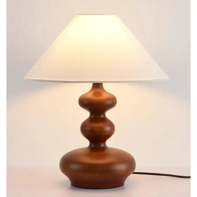 Milk-white linen fabric shade (soft light transmission), walnut wood-textured rounded lamp body. Warm light through fabric...