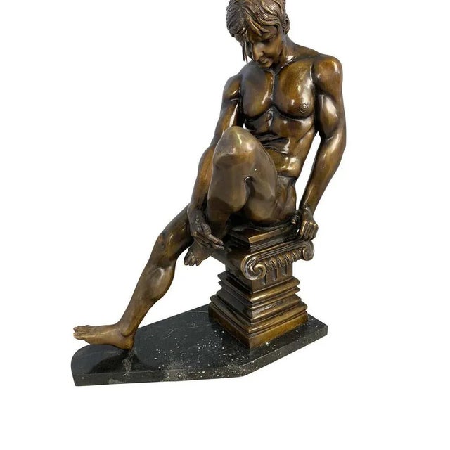 A handsome 20th century bronze wrestler posing on a corinthian plinth. The muscular figure is holding his left foot in a...