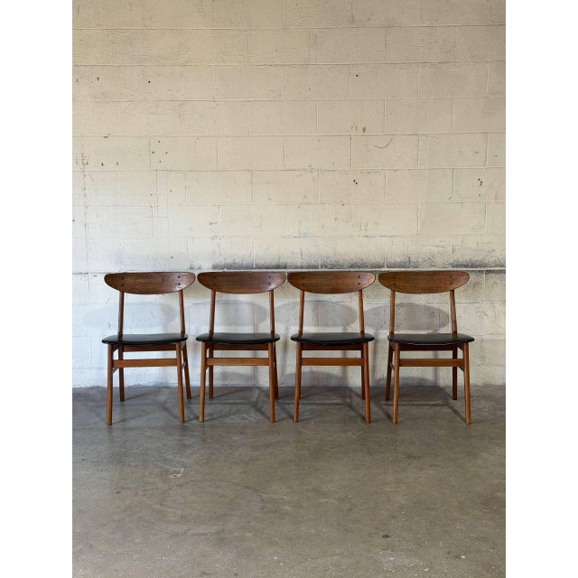 This set of four dining chairs features gently curved solid teak backrests and clean tapered legs. Black upholstery...