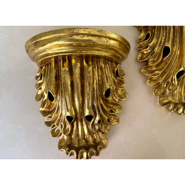 Pair of late 20th century Hollywood Regency wall shelves in a gold finish. Feature a romantic draped fabric look. Please...