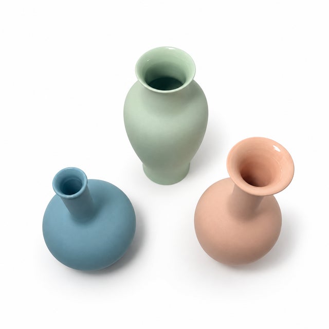 Sculptural set of three Middle Kingdom porcelain vases in soft pastel pink, celadon green, and blue. Each features a...
