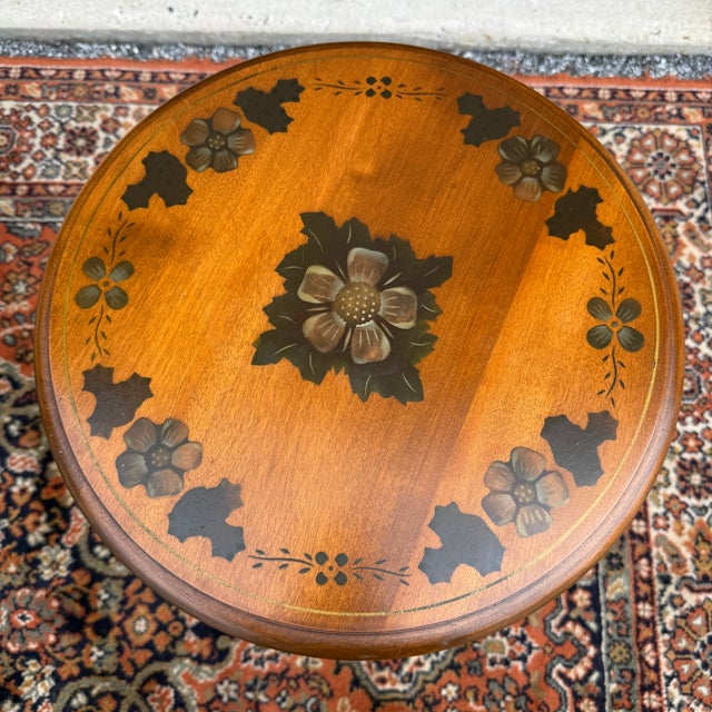 A vintage Ethan Allen Rustic Farmhouse solid maple accent table having a round stenciled top with flower motifs over a...