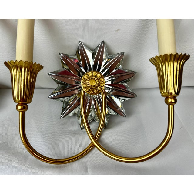 Pair of gilt two light sconces each with a mirrored 12 point starburst. The gilt finish and mirrored appointments give...
