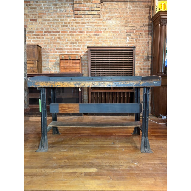 Rugged and weathered industrial table with heavy duty steel base and thick wooden top aged with a bluish-gray patina. Has...