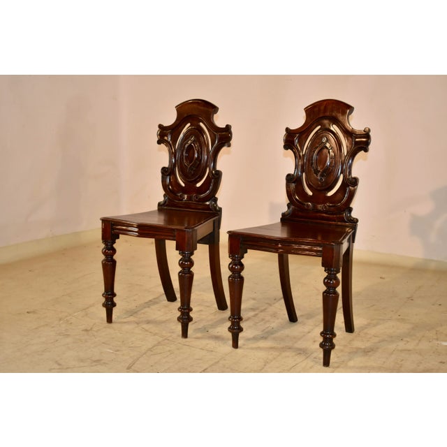 Pair of 19th century mahogany hall chairs from England. The backs are in the shape of shields, which are pierced and have...