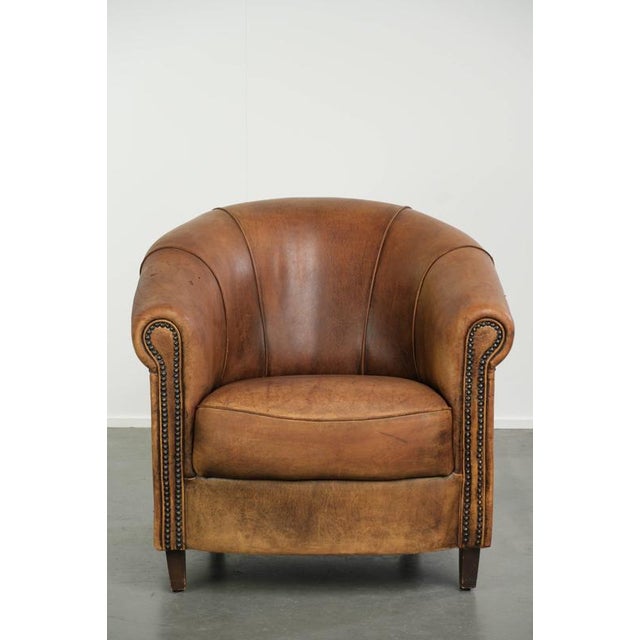 This lovely vintage sheepskin club armchair offers a comfortable seat thanks to the fixed seat cushion. The armchair is...