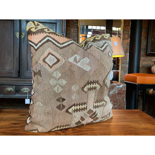 This custom pillow is made from a fragment of an antique, handwoven Kilim rug. The design features geometric motifs of...