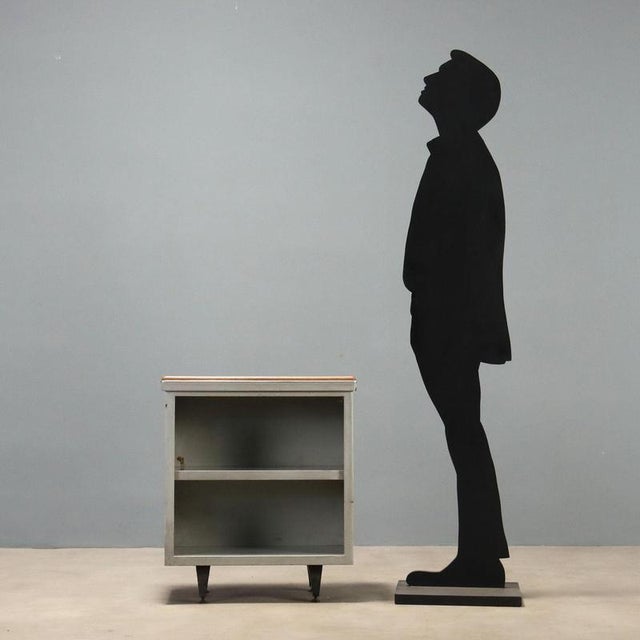 1960s metal cabinet characterized by an essential and functional design. The cabinet features an open compartment divided...