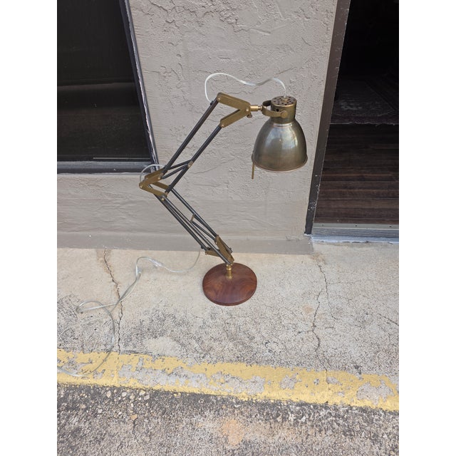 Attractive contemporary desk lamp with adjustable arm and round wood base.