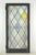 Tudor style casement stained glass window with a leaded diamond pattern in a pastel color scheme. The frame is made of...