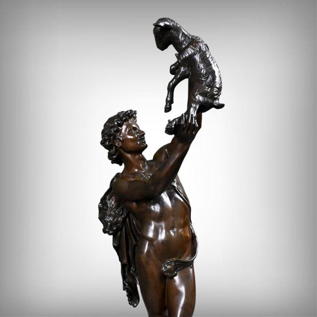 An elegant bronze with a brown patina depicting a young man carrying a kid over his head, attributed to the sculptor...