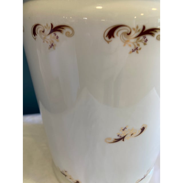 This porcelain trashcan features a smooth white glaze accented with red and gold scrolling floral motifs, offering a...