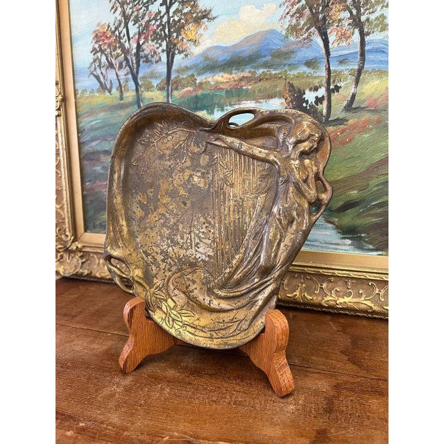 This sturdy possibly trinket/ jewelry tray or wall art depicts a woman with a harp and other nature elements. This Piece...