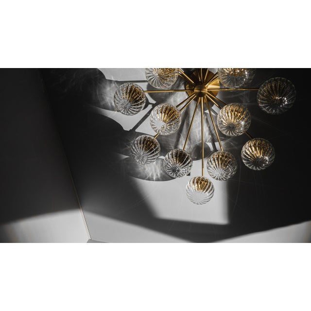 This oval arrangement of lights explodes into a brass and glass sunburst, spreading across the ceiling. A constellation of...