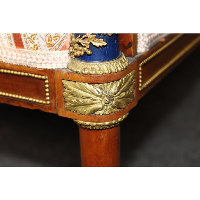 This elegant bronze-mounted and ebonized settee is a sophisticated interpretation of the celebrated Neoclassical designs...