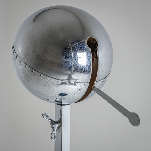 Metal floor lamp with a spherical shade featuring decorative rivet details. The shade features a swivel arm, allowing the...