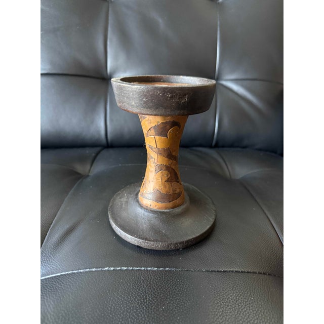 Striking handcrafted candlestick with a primitive, sculptural character. The substantial charcoal-black circular base and...