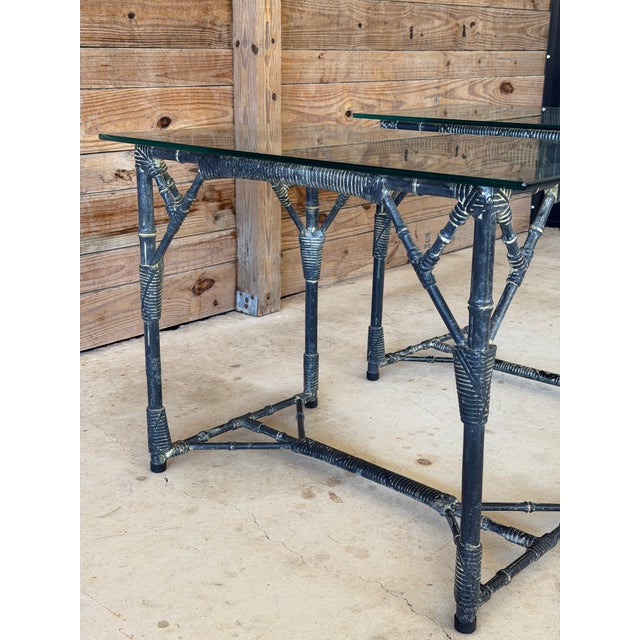 A chic pair of vintage faux bamboo aluminum side tables featuring sculptural bases and clean-lined glass tops. The frames...