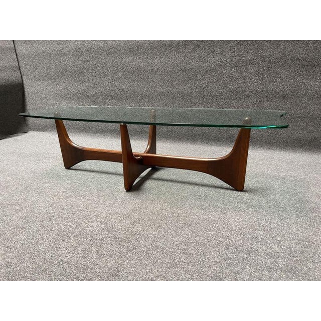MCM Coffee table featuring a wood base and a clear glass top. The design includes intersecting wooden supports and an...