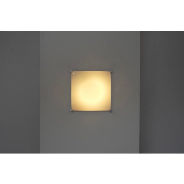 "Bolla" wall or ceiling light with a square aluminum base and a curved white plastic diffuser. Designed by Elio Martinelli...