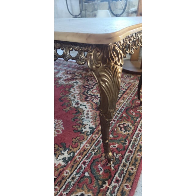Elegant vintage french coffee table featuring a beautifully veined real marble top set upon ornate solid brass cabriole...