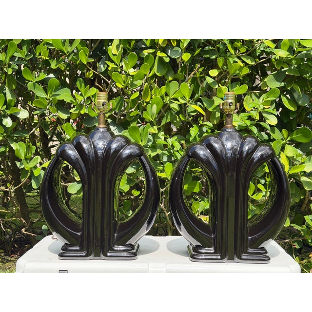 Striking pair of vintage sculptural ceramic table lamps in a glossy black finish. The bold, architectural forms have a...