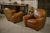 Pair of cognac-colored leather club chairs, offering enveloping comfort and generous proportions. with their rounded...
