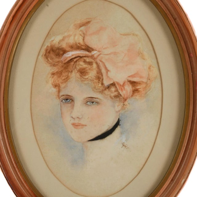 This Oval Framed Watercolor Portrait presents the delicate likeness of a young woman with softly blushed cheeks, pale blue...