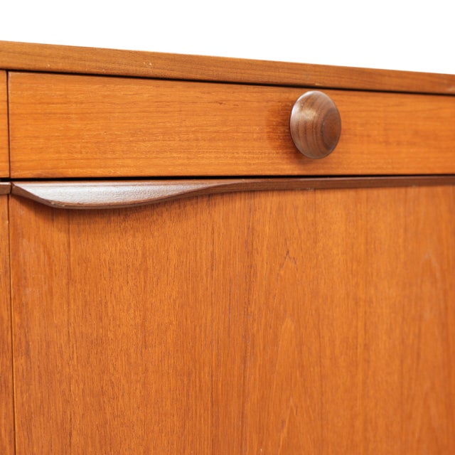 Elegant mid-century teak sideboard by Elliots of Newbury (EON), England, featuring clean lines, sculptural wooden pulls,...