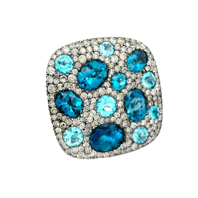 A striking fashion ring featuring a stunning array of oval and round blue topaz stones. The design showcases a vibrant mix...