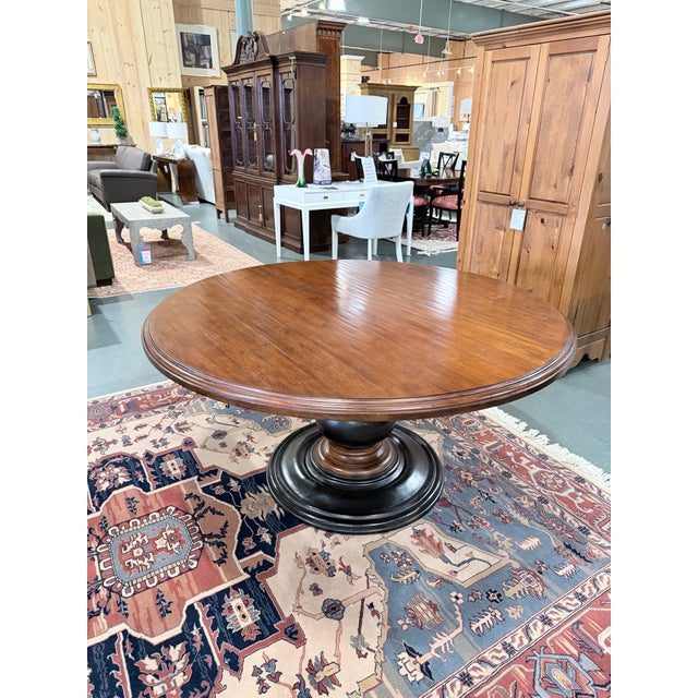 This is a beautifully proportioned Hekman round dining table featuring a richly grained wood top with a warm walnut tone....