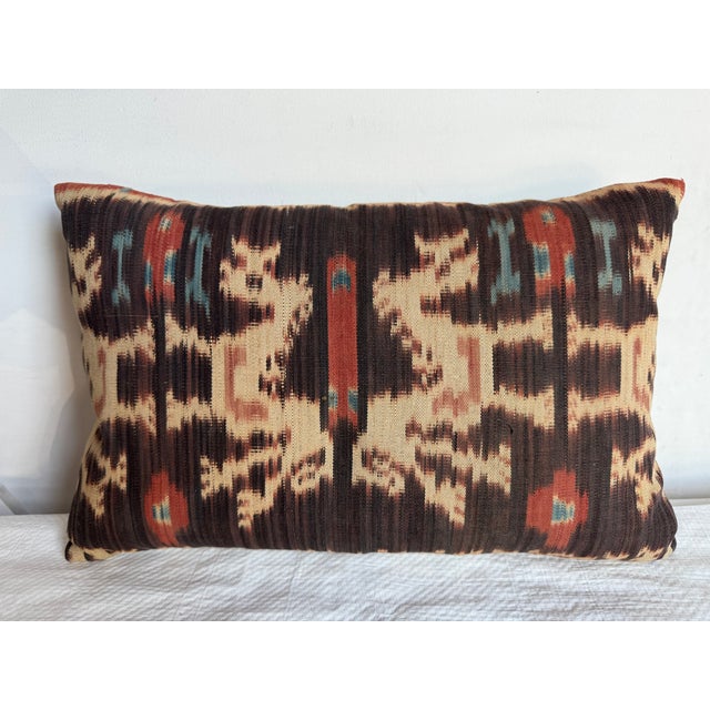 This stunning vintage Ikat pillow, crafted in 1850, boasts a striking geometric design in burnt orange, beige, and teal....