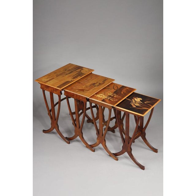 Gallé marquetry nesting tables in different woods, decorated with iris, wisteria, a frog on a water lily and umbellifers,...