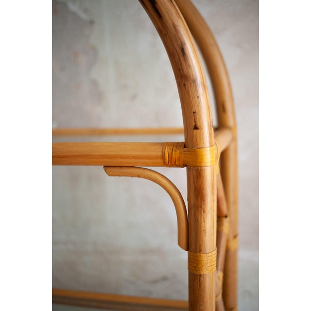 Arched bamboo structure with geometric designs on the sides. Four glass shelves and visible rattan bindings.