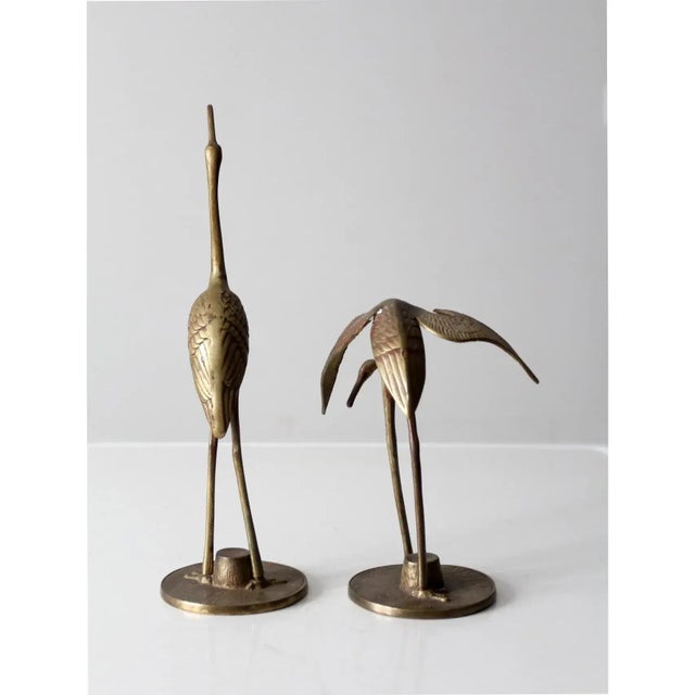 A pair of mid-century brass crane sculptures featuring finely detailed craftsmanship that captures the graceful elegance...