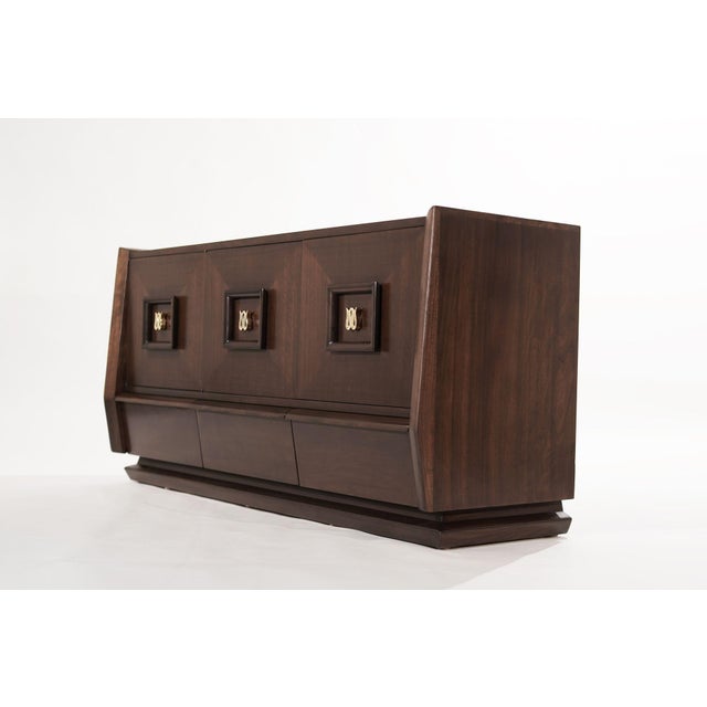 A walnut dresser original from Italy, circa 1950-1959. Featuring swooping curves and sudden edges, the three doors open up...