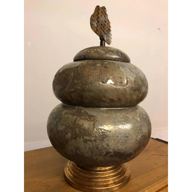 Tony Evans signed raku pottery with handmade glass handle. It features a double high bulbous body with a stepped gold...