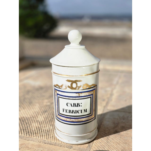 Beautiful pair of white porcelain antique apothecary jars from Europe. These have worn gold, blue and black details. One...