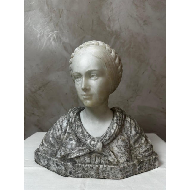 Elegant Carrara marble bust of a woman, signed Pugi on the base. This sculpture depicts a young woman with a delicate face...