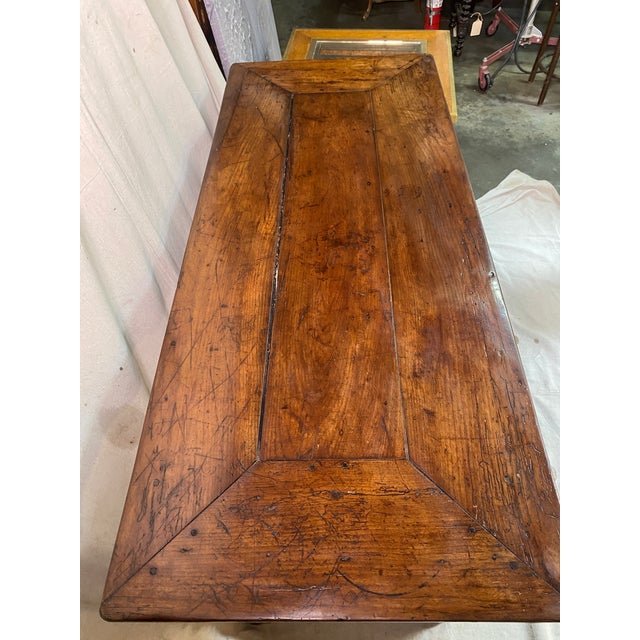 French Country table with 4 turned legs. Joined with a stretcher on center. Top has an enveloped shaped wood frame top....