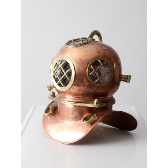An original copper diving helmet circa 1930s-1940s. This authentic piece features viewing ports, a neck ring, and fittings...