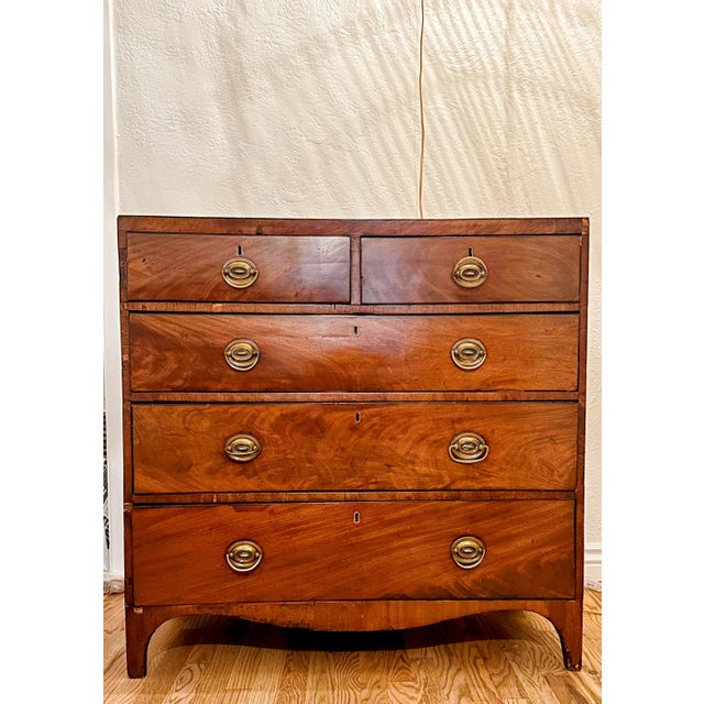 A handsome antique British chest featuring mahogany and walnut veneers with decorative inlay, richly figured drawer...