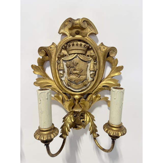 Carved in high relief and finished in a warm gilded surface, this matched pair of French wall sconces presents the...