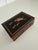 Early 20th century marquetry box with hidden latch mechanism. 5.75” x 3.75” x 2”. Wood inlay depicting fox hunt scene