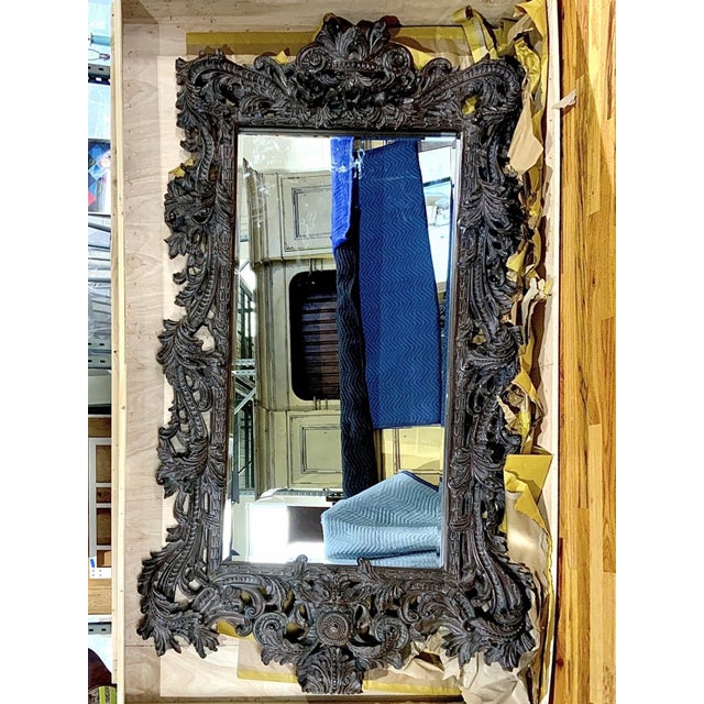 An ornate, palatial-sized Rococò style rectangular beveled glass wall mirror in a dark, aged wood finish with a heavily...