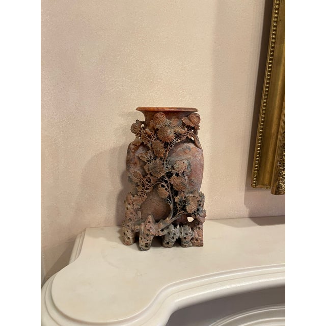 A hand-carved soapstone vase in mottled russet and grey tones, with natural veining and warm reddish and taupe variations...