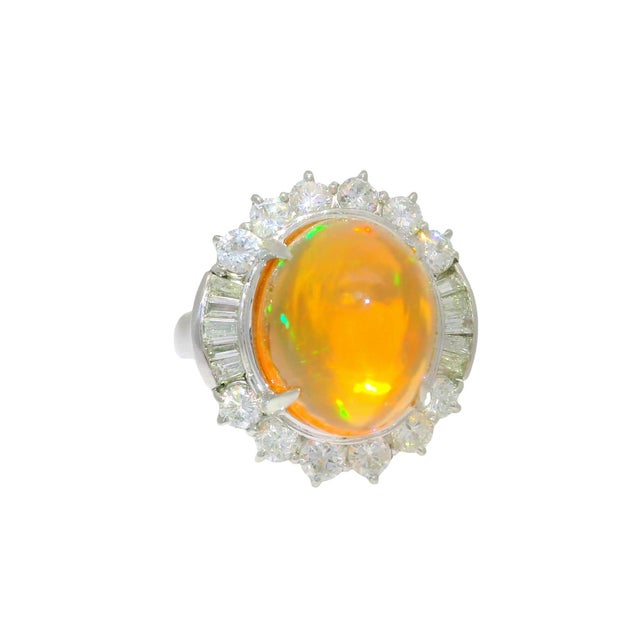 A striking platinum cocktail ring featuring a captivating fire opal at its center. The opal weighs 8.26 carats and...